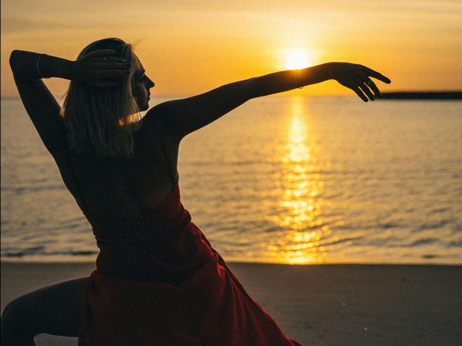 Retreat guests dancing together at sunset on a Greek beach